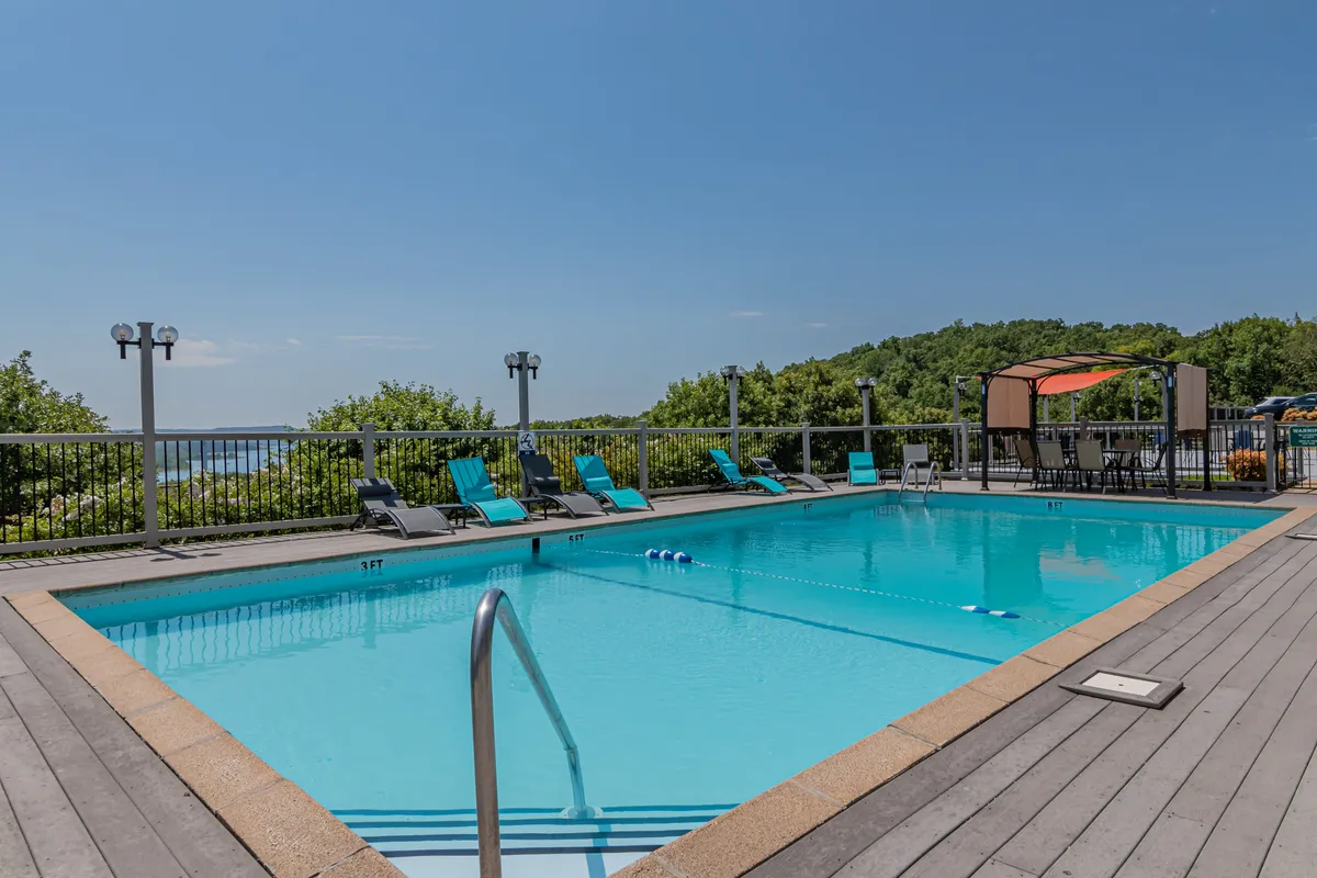 An inviting outdoor swimming pool surrounded by lounge chairs and landscaped gardens. The pool area offers ample space for relaxation, socializing, and enjoying the sun, with a scenic backdrop ideal for summer fun.