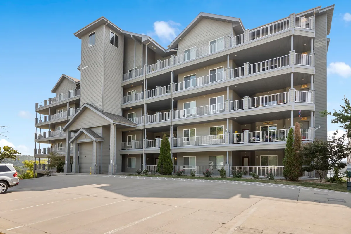 The welcoming facade of the condo building, featuring multiple balconies, a clear entrance area, and lush green surroundings. The photo highlights easy access and shared outdoor spaces, with a tranquil, inviting mood that suggests both relaxation and community living.