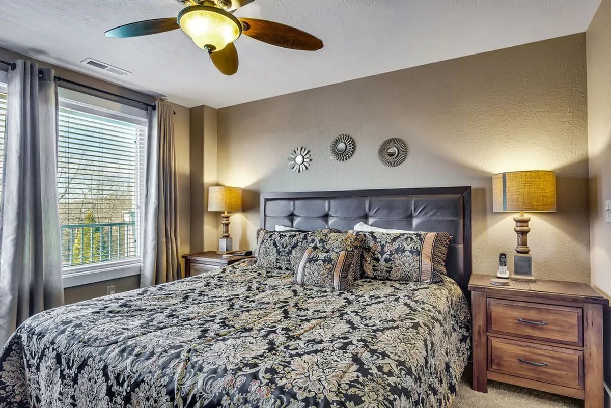 This image presents a restful bedroom with a king-size bed adorned with decorative bedding, well-coordinated nightstands with lamps, and a window filtering in natural light. The space feels cozy and inviting, ideal for unwinding after a busy day.