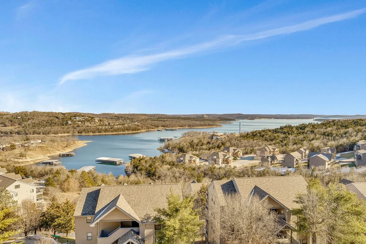 A tranquil, panoramic view of Table Rock Lake at sunset, framed by natural vegetation and dotted with lakeside houses. The scene conveys the serene beauty of the shoreline and hints at the abundance of outdoor activities possible right from the lakeshore.