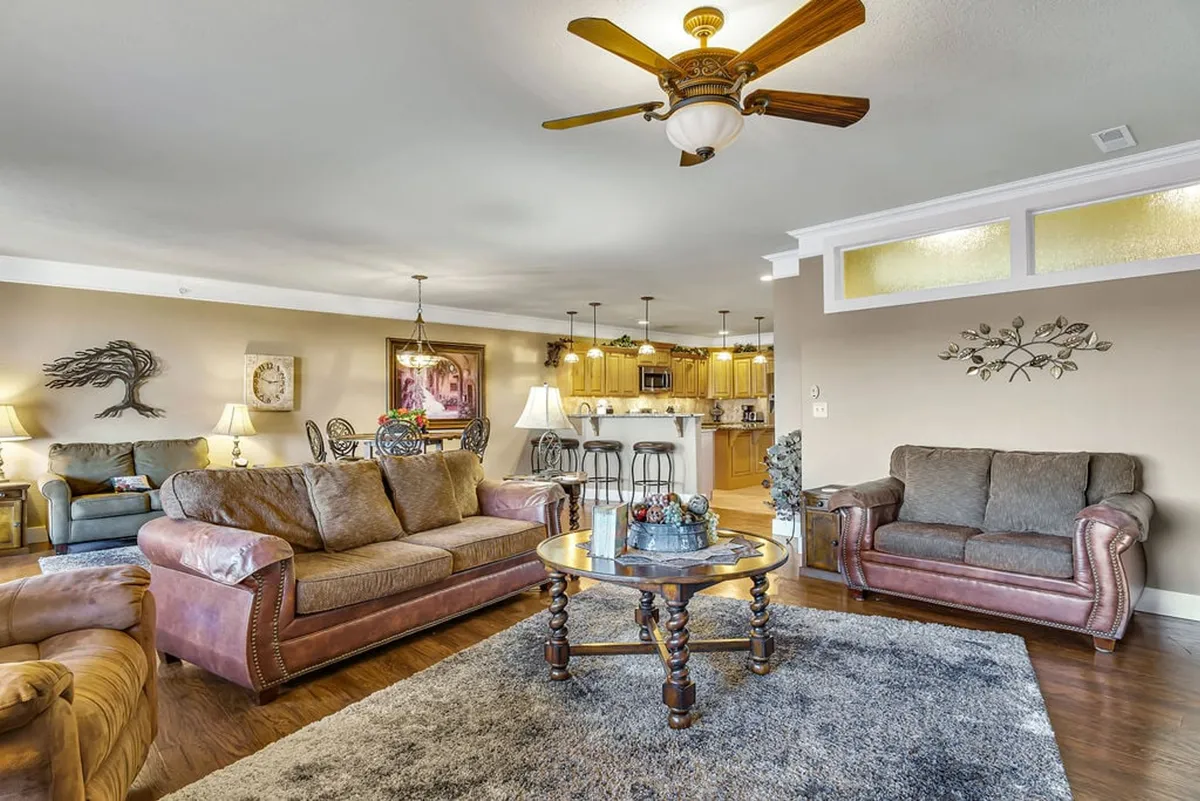 The hero image showcases a stylish and spacious living area featuring plush sofas arranged around a modern coffee table, accented with tasteful wall art. The inviting setting is perfect for relaxing, with an electric fireplace adding warmth and ambiance, ideal for family gatherings or cozy evenings. Natural light floods the room, emphasizing the open layout and contemporary decor.