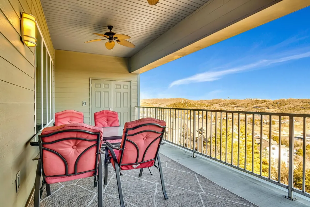 An exterior shot of a private deck furnished with an outdoor dining set and ceiling fan, overlooking the scenic landscape. The space is perfect for al fresco dining, morning coffee, or sunset relaxation while enjoying the tranquil lake vistas.