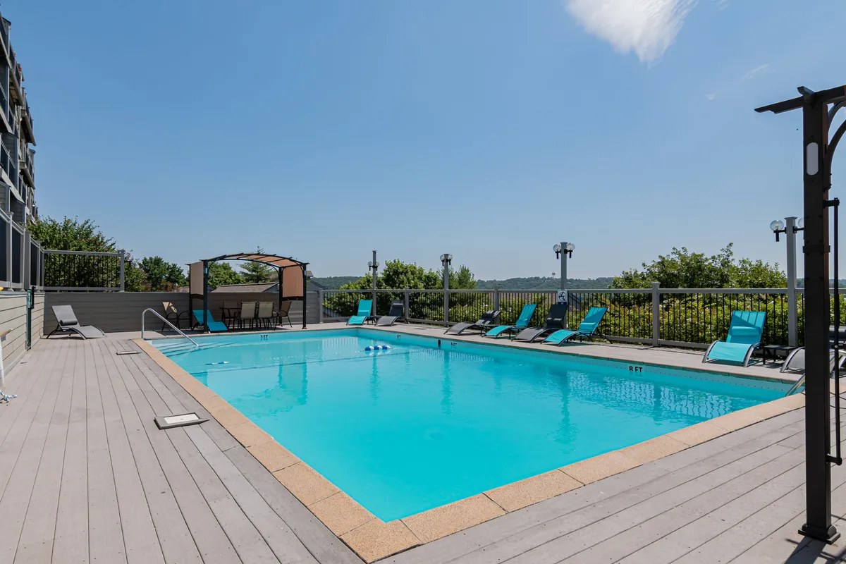 A vibrant, inviting swimming pool area with lounge chairs and a canopy structure, surrounded by lush greenery. The relaxed atmosphere suggests both relaxation and fun for families, with space for socializing, swimming, and unwinding after a day of adventure.