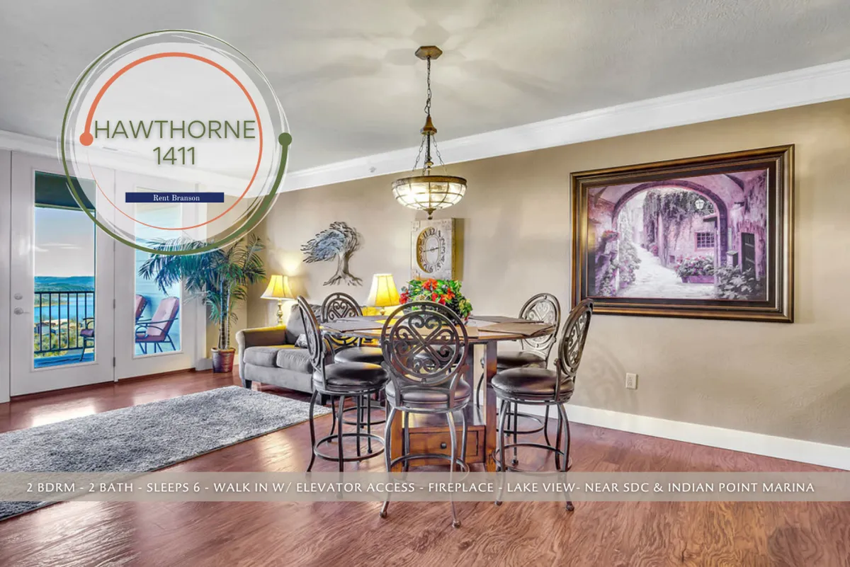 This image showcases a beautifully set dining table with an adjacent electric fireplace and expansive windows offering panoramic views of Table Rock Lake. The room features tasteful artwork, indoor plants, and a warm, inviting ambiance that encourages gathering and relaxation.
